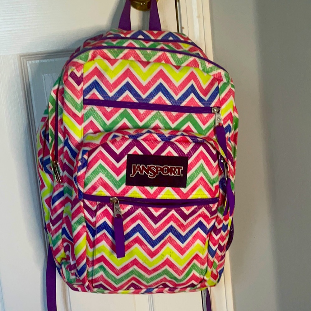 A pink,purple,yellow,and green  JanSport backpack.